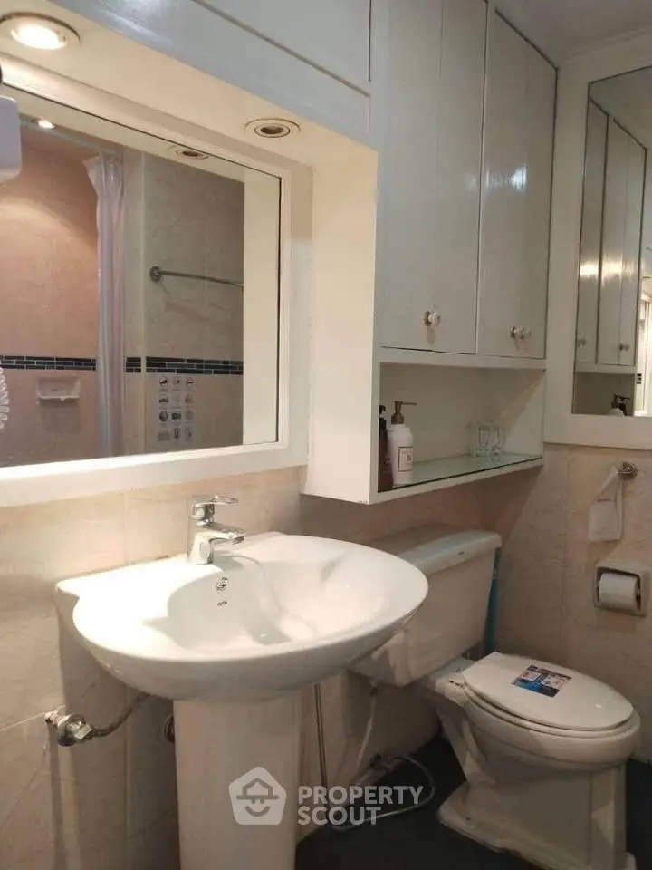 Charming bathroom with pedestal sink and ample storage cabinets.