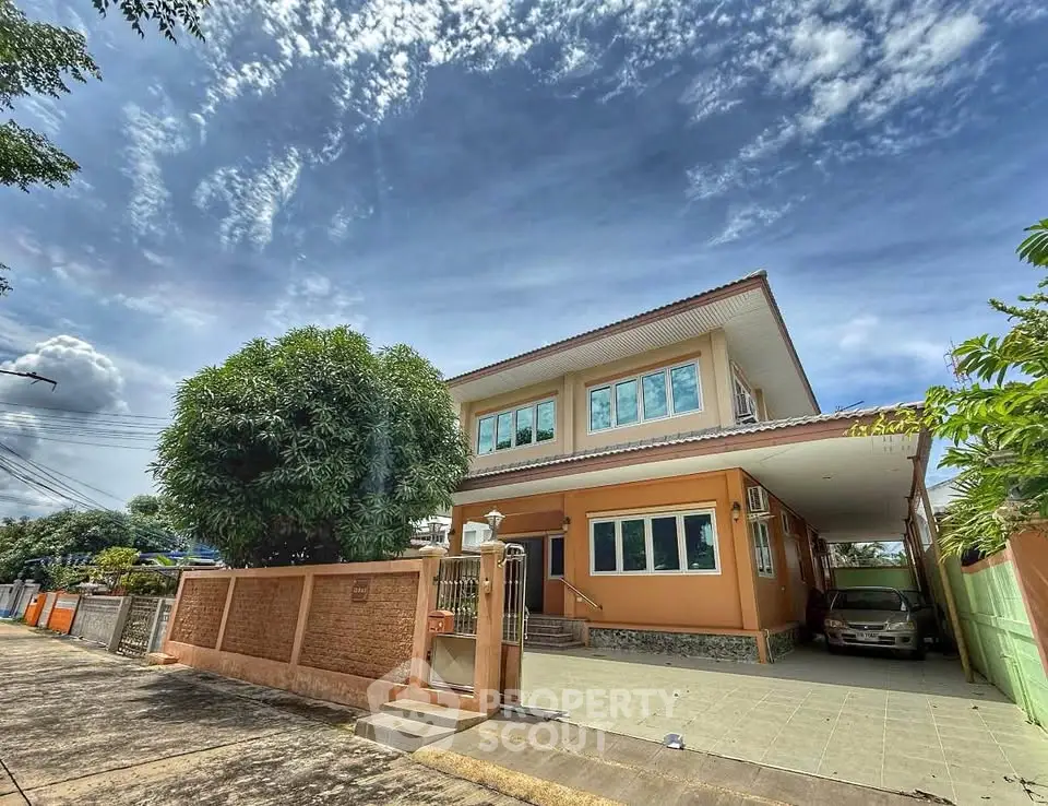 Charming two-story house with spacious driveway and lush greenery under a vibrant sky.
