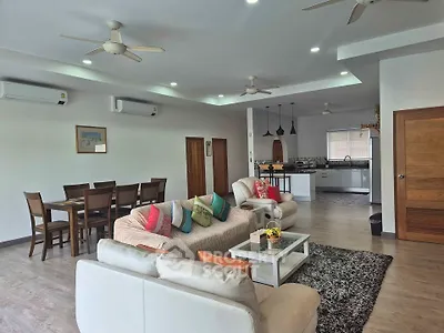Spacious open-plan living room with modern kitchen and dining area, featuring stylish decor and ample natural light.