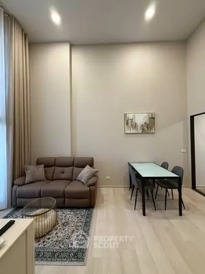 Modern living room with high ceilings, elegant sofa, and dining area in a stylish apartment.