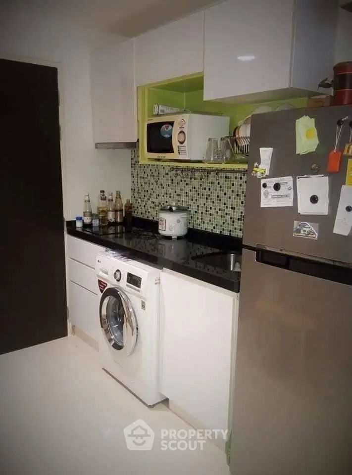 Modern kitchen with washing machine and sleek appliances in compact layout.