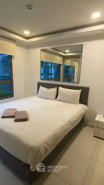 Modern bedroom with large mirror and cozy bed in stylish apartment.