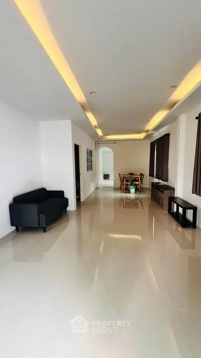 Spacious modern living room with sleek tile flooring and elegant recessed lighting.
