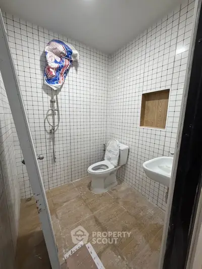 Modern bathroom with tiled walls, toilet, and shower in a real estate property.