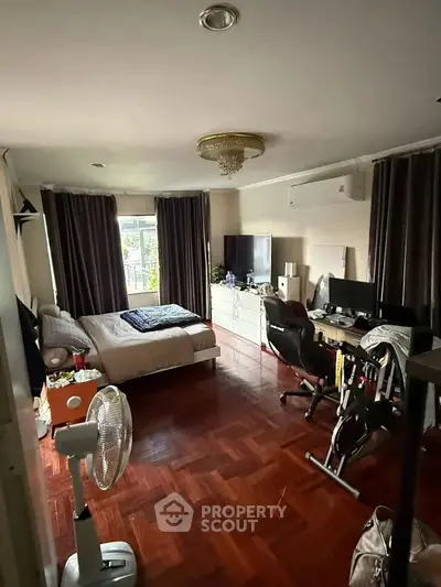 Spacious bedroom with hardwood floors, large window, and modern furnishings.