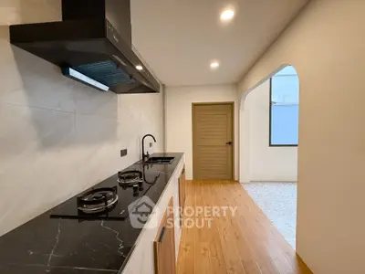 Modern kitchen with sleek black countertop and gas stove in a stylish apartment.