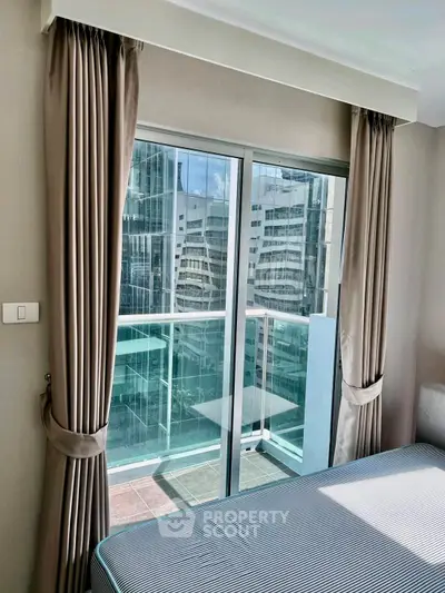 Modern bedroom with balcony and city view, featuring elegant curtains and sleek design.
