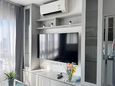 Modern living room with sleek TV setup and air conditioning, featuring stylish decor and natural light.