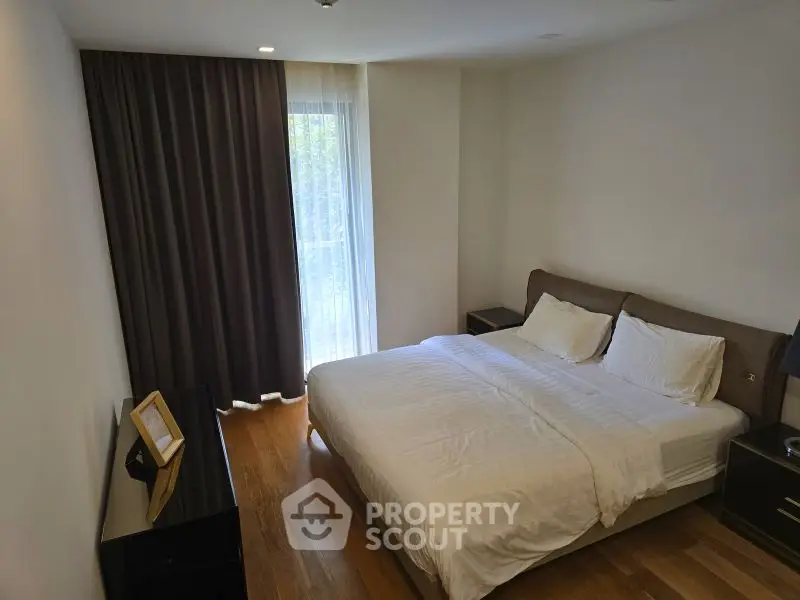 Cozy bedroom with elegant decor and natural light from large window.