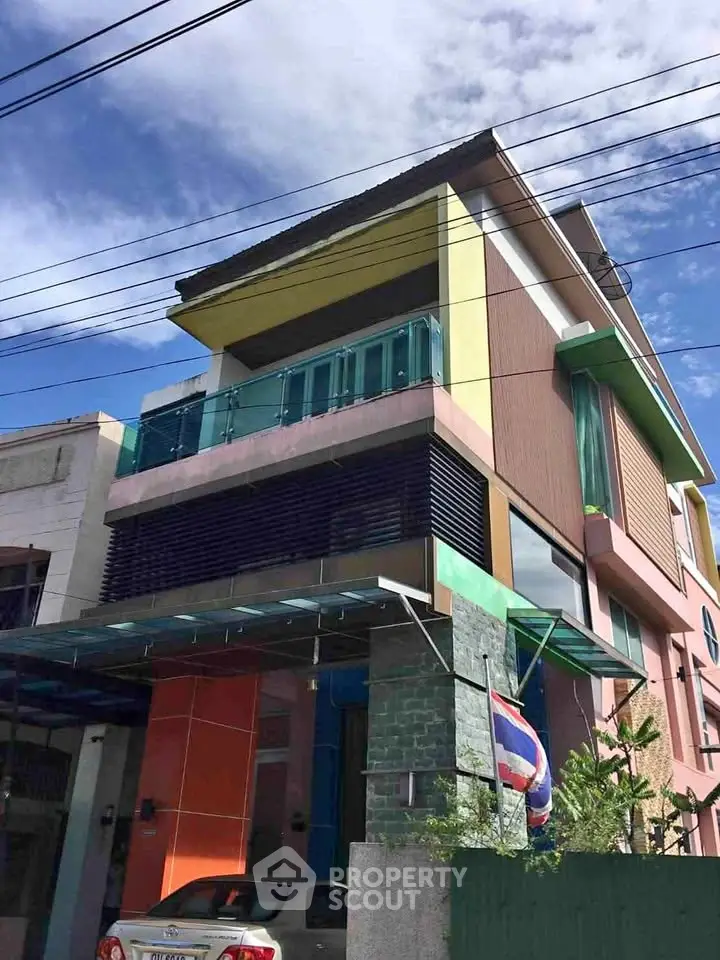 Modern multi-story building with colorful facade and glass balcony, showcasing contemporary architectural design.