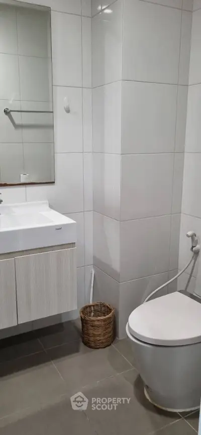 Modern bathroom with sleek fixtures and neutral tiles, featuring a stylish vanity and toilet.