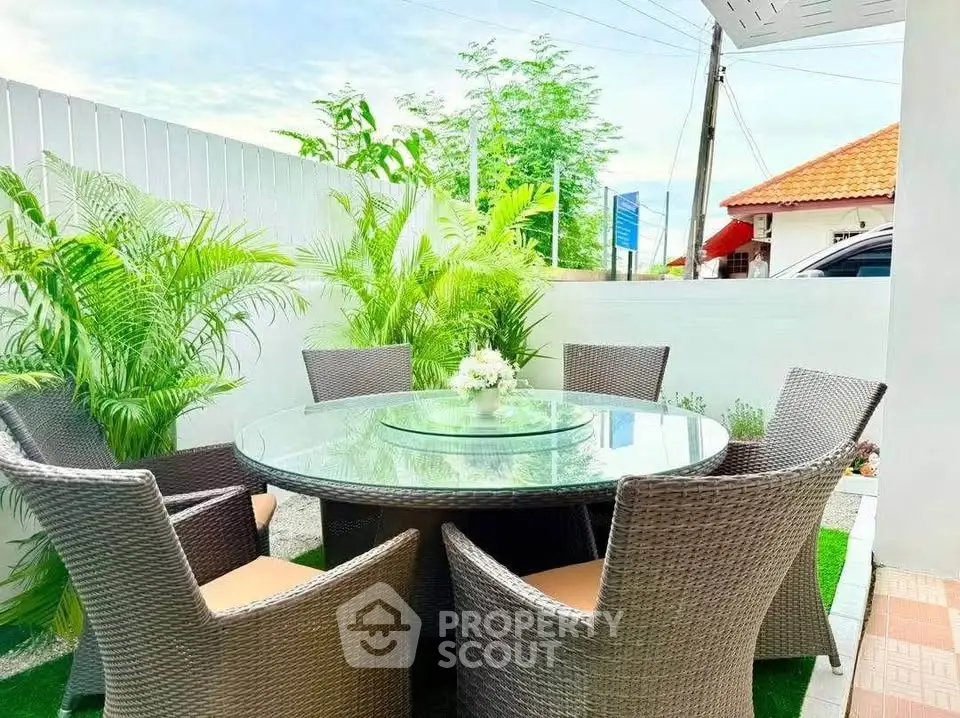 Charming outdoor patio with elegant wicker furniture and lush greenery, perfect for relaxing and entertaining.