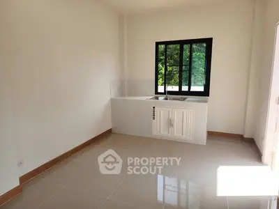 Bright empty kitchen with sleek tile flooring and large window view.