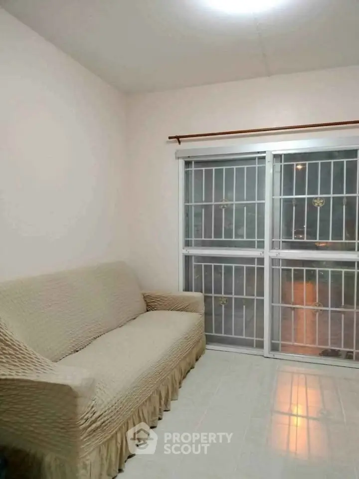 Cozy living room with a comfortable sofa and large window with security bars.