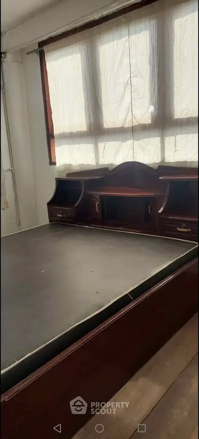 Spacious bedroom with large window and built-in wooden furniture, perfect for cozy living.
