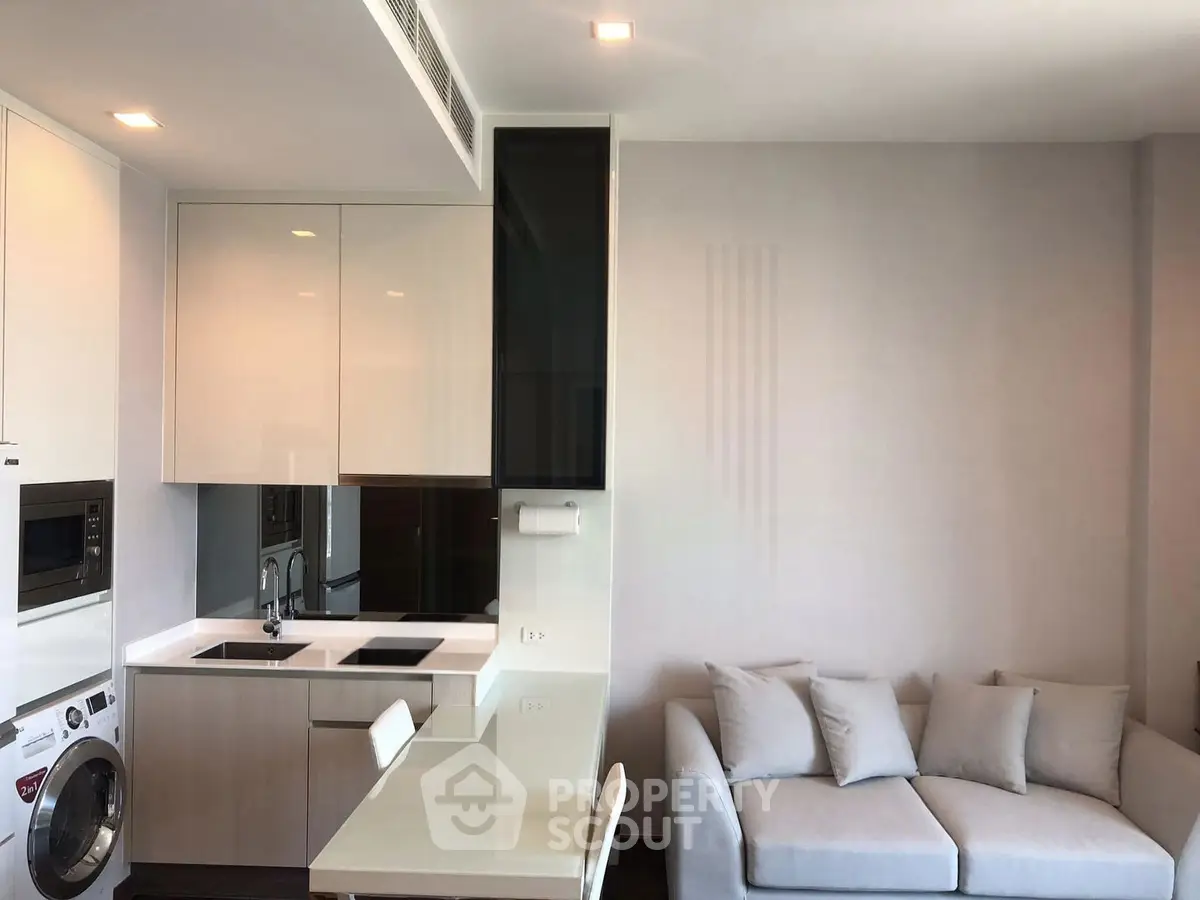 Modern open-layout kitchen and living room with sleek appliances and cozy seating area.