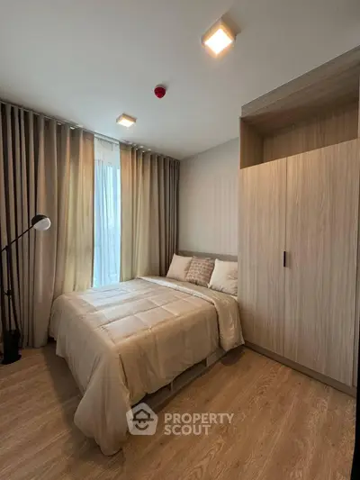 Cozy bedroom with modern decor and ample natural light, featuring a stylish wardrobe and elegant lighting.