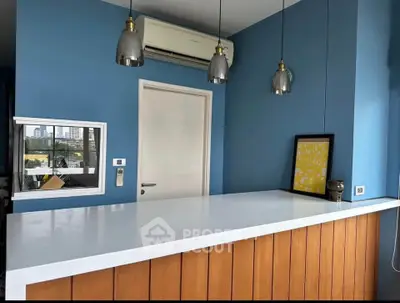 Modern kitchen with blue walls, white countertop, and stylish pendant lights.