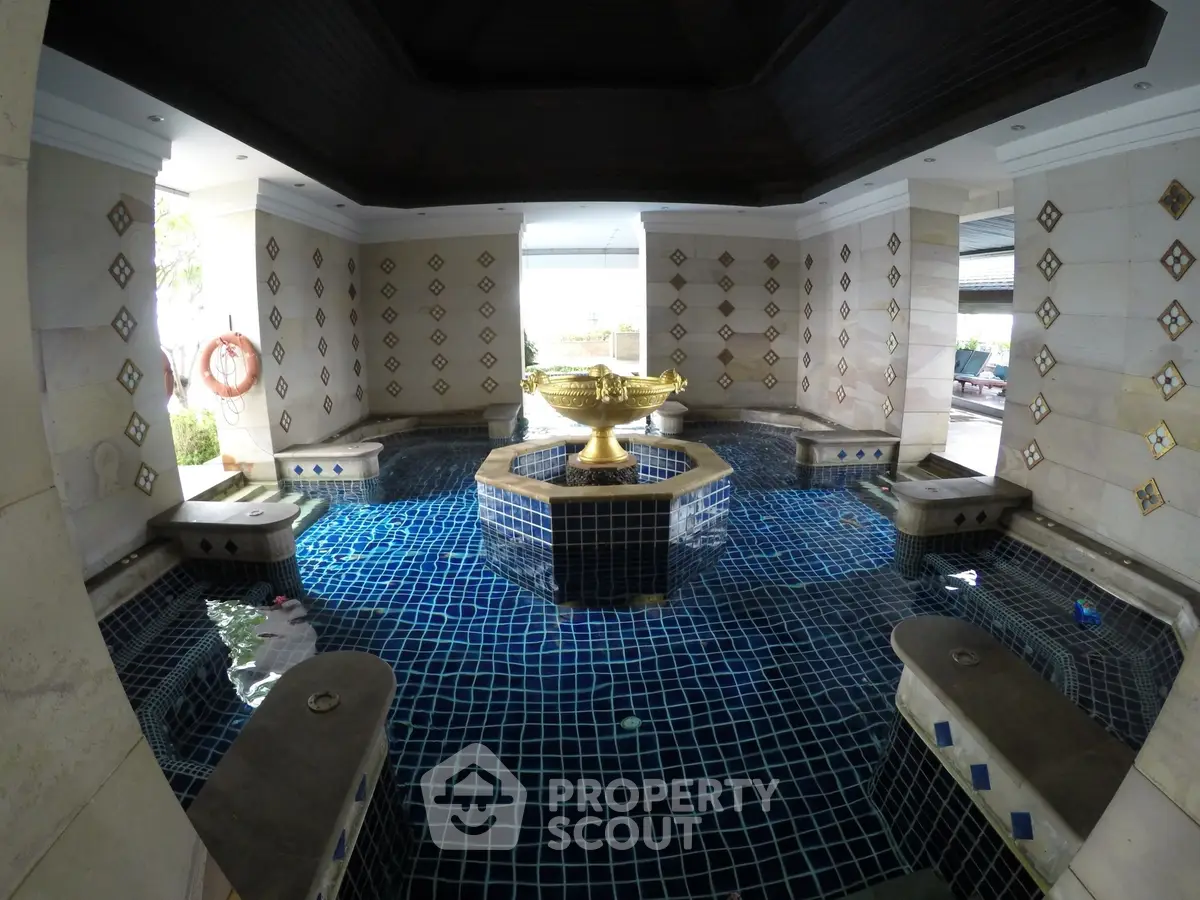 Luxurious indoor pool with elegant tile design and decorative fountain centerpiece.