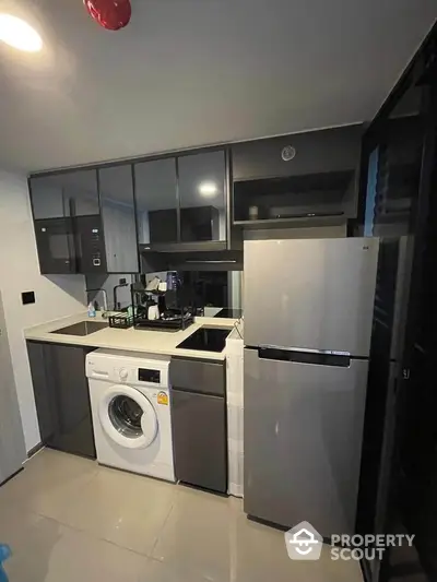 Modern compact kitchen with washing machine and fridge in sleek design