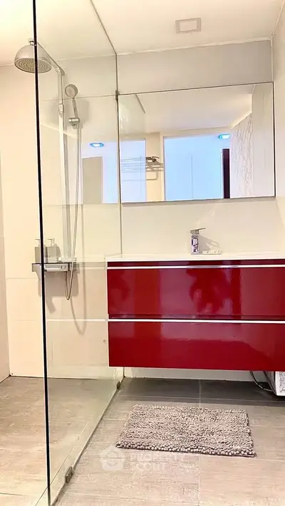 Modern bathroom with sleek red vanity and glass shower enclosure.