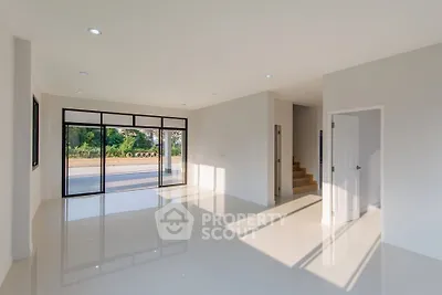 Spacious modern living room with large windows and glossy floors, offering abundant natural light and serene views.