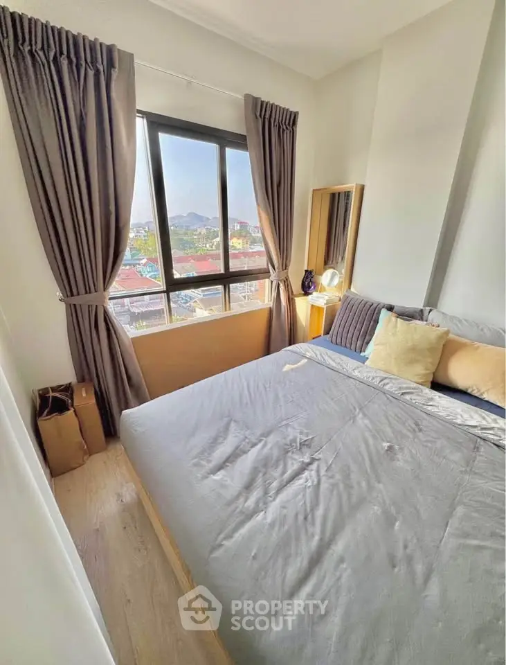 Cozy bedroom with large window offering scenic city views, featuring elegant curtains and modern decor.