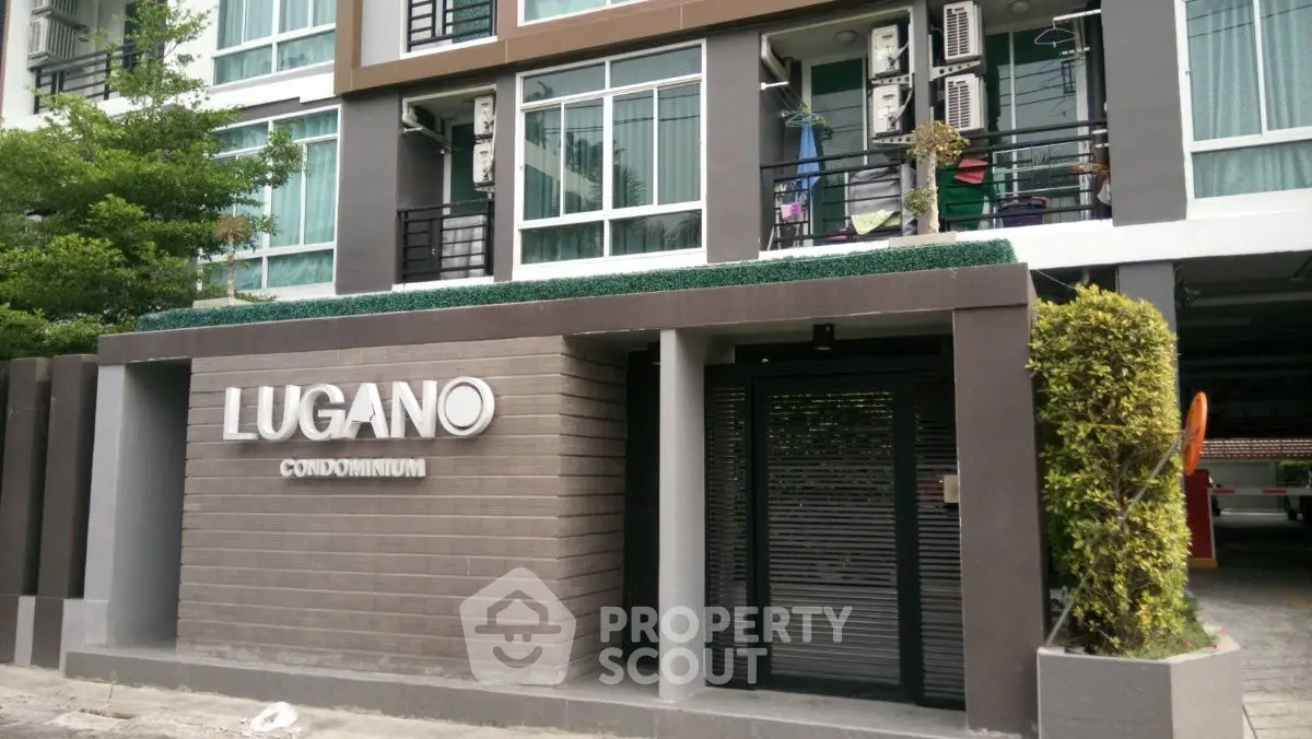 Modern condominium entrance with sleek design and lush greenery at Lugano.