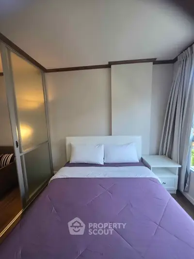 Cozy bedroom with purple bedding and natural light from window