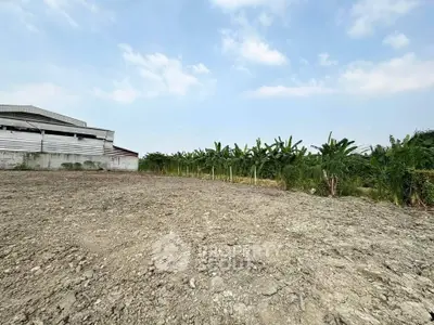 Expansive land plot with potential for development, surrounded by lush greenery and clear skies.