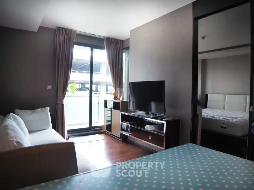Modern living room with TV, sofa, and balcony access in a stylish apartment.