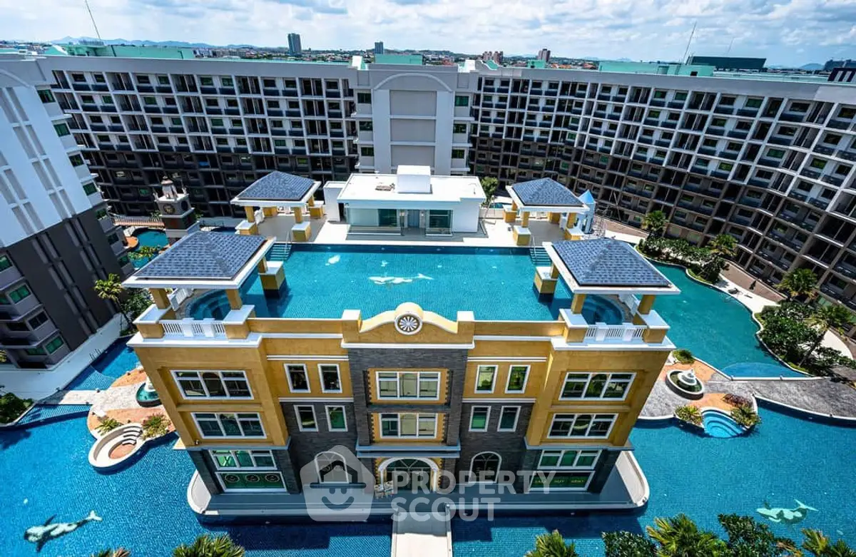 Stunning aerial view of luxury condominium with expansive pool and modern architecture.