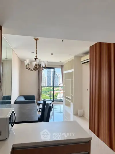 Modern living room with city view, elegant chandelier, and open layout in high-rise apartment.