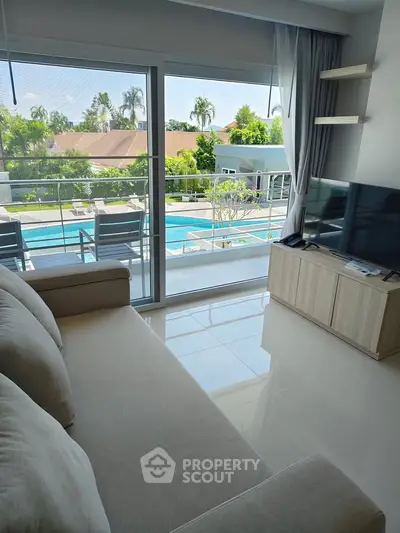 Modern living room with pool view, featuring sleek furniture and large windows for natural light.
