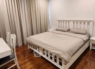 Spacious bedroom with elegant wooden flooring and cozy bed setup.