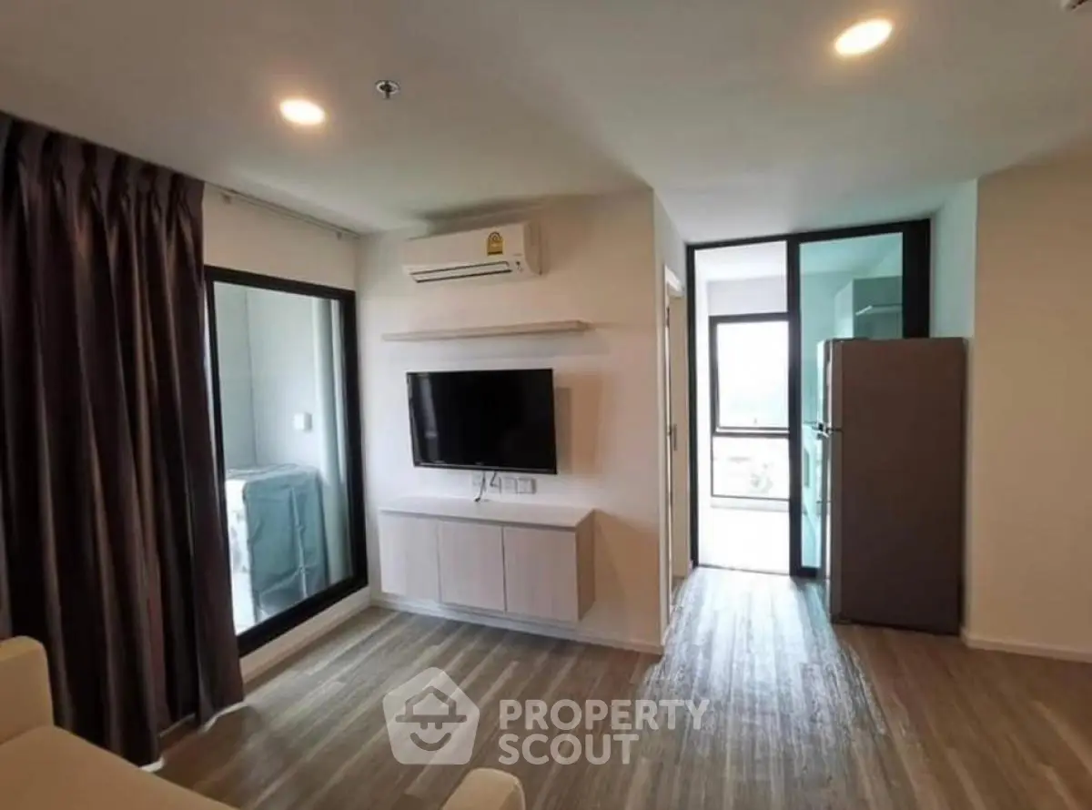 Modern living room with sleek design, featuring a wall-mounted TV and large windows for natural light.
