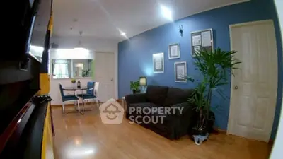 Modern living room with blue accent wall, cozy sofa, and dining area in open layout apartment.
