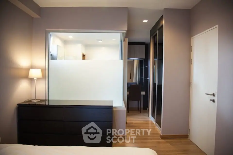 Modern bedroom with sleek design and wooden flooring, featuring a stylish dresser and a cozy ambiance.