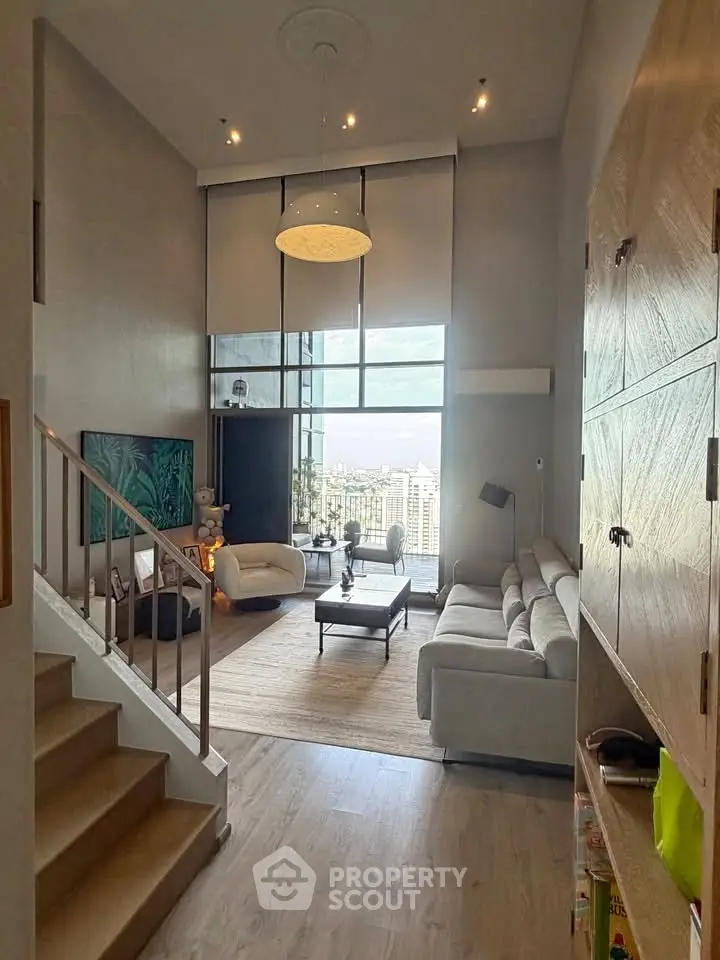 Spacious modern living room with high ceilings and large windows offering a stunning city view.