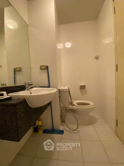 Modern bathroom with sleek fixtures and minimalist design, featuring a wall-mounted sink and toilet.