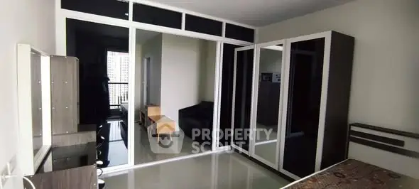 Spacious bedroom with modern wardrobe and city view balcony access.