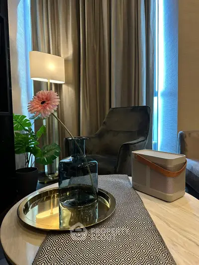 Elegant living room with modern decor, featuring a stylish armchair, floor lamp, and decorative vase on a chic table.