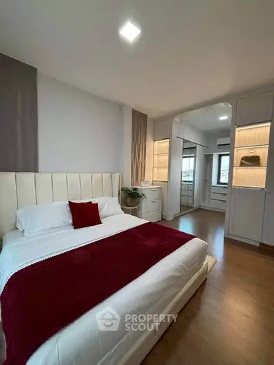 Modern bedroom with elegant decor and wooden flooring, featuring a cozy bed and stylish built-in storage.