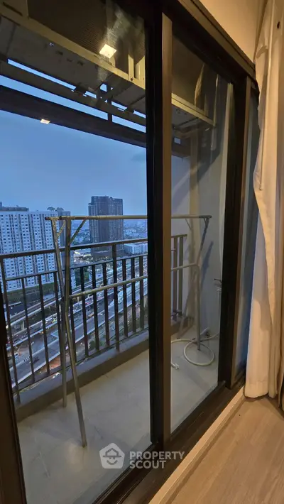 High-rise apartment balcony with city view and sliding glass doors.