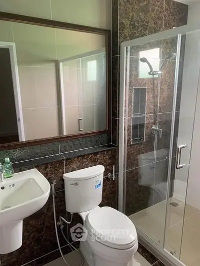 Modern bathroom with glass shower and elegant dark tile design.