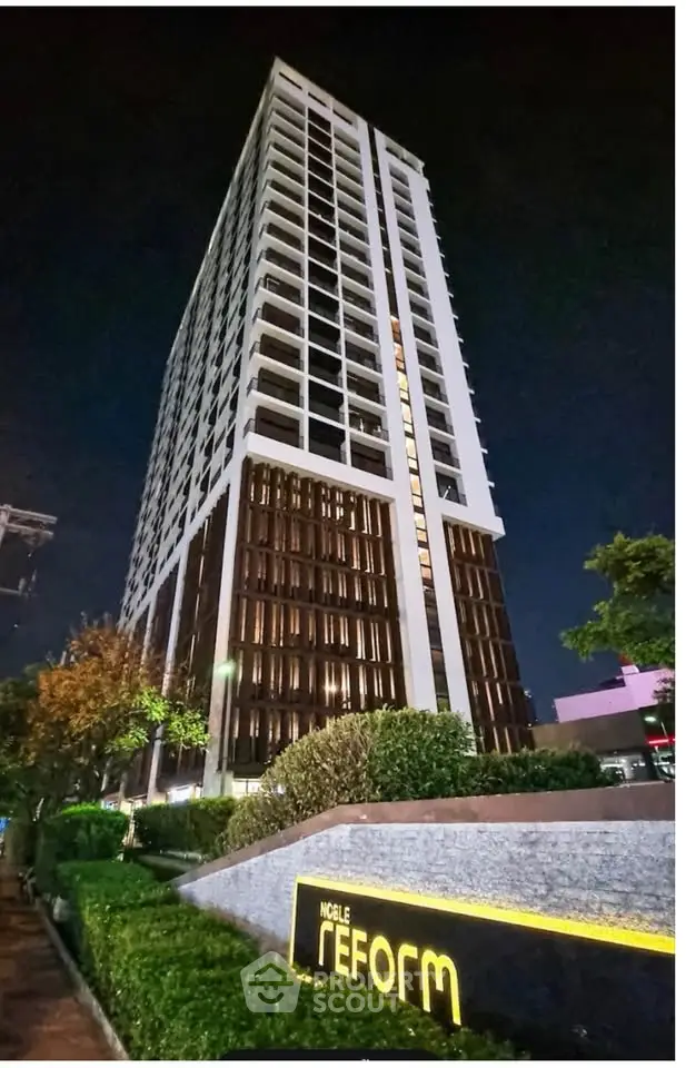 Stunning night view of a modern high-rise building with lush landscaping.