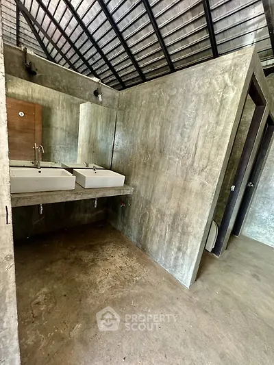 Modern industrial-style bathroom with concrete walls and dual sinks.