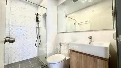 Modern bathroom with sleek shower and stylish vanity in contemporary apartment.