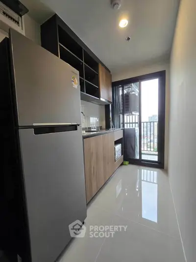 Modern kitchen with sleek appliances and balcony view in urban apartment