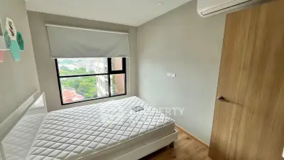 Cozy bedroom with large window offering city view, featuring a comfortable bed and modern air conditioning.
